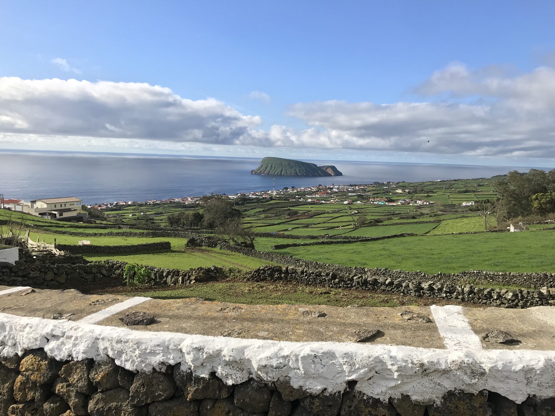 Terraced green fields, a hillside village, and an island in the Atlantic