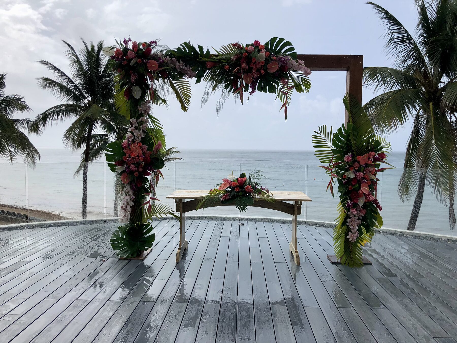A floral wedding arch on a deck overlooking the ocean